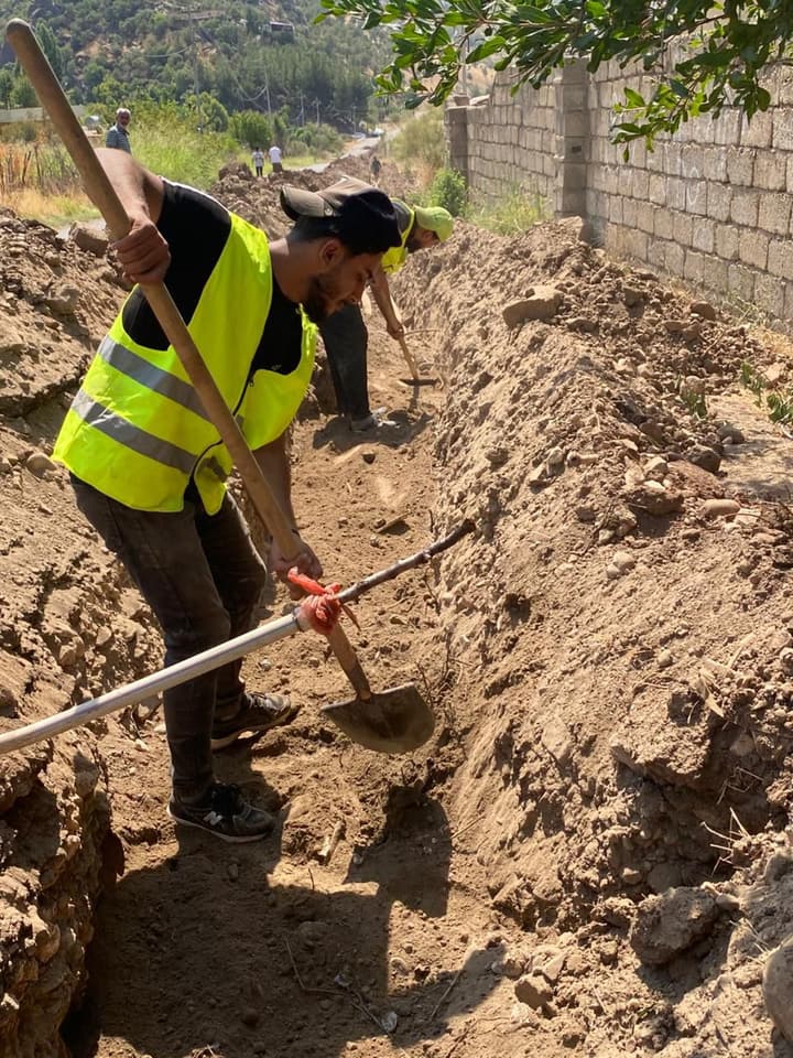 Workers installing pipe in a trench
