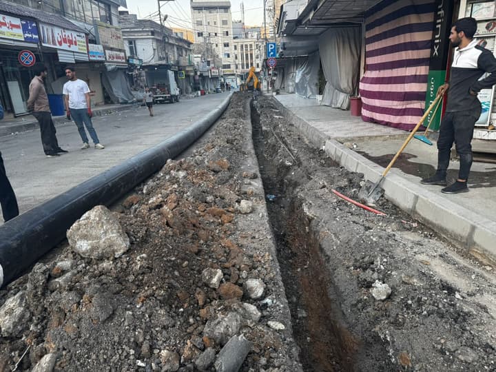 Workers installing pipe in a trench